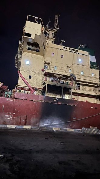 The bulk carrier MJ Pinar alongside in Odesa at night, name on the bridge front and scorched hull after the strike